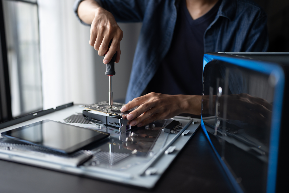 A technician using a screwdriver to install a new SSD or hardware component into an open desktop computer case, demonstrating a PC performance upgrade.